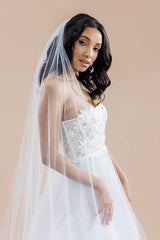 Side profile of a modern romantic bride wearing a strapless dress with the Monet Beaded Blossom Cathedral Veil draped over her shoulder. Laura Jayne Accessories Toronto. Made in Canada.