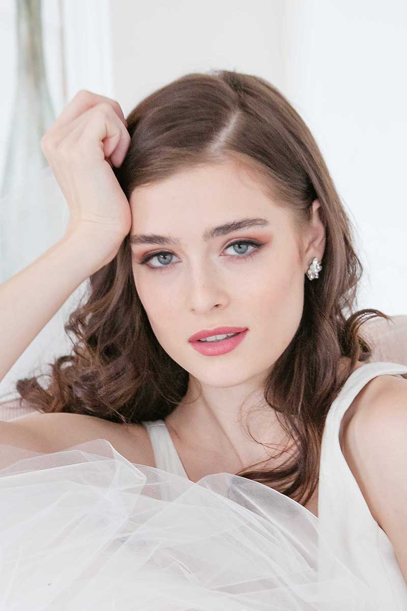 Woman with hand on head wearing E7023 crystal pearl post earrings by Laura Jayne Accessories