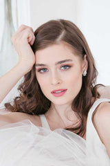 Woman with hand on head wearing E7023 crystal pearl post earrings by Laura Jayne Accessories