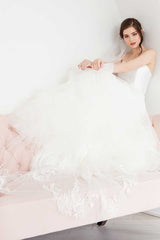 Bride sitting on corner edge of the sofa wearing hand embroidered floral Indra Cathedral veil with train cascading over the side.