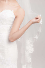 Bride holding French lace edge of Laura Jayne Marlisa fingertip veil. Handcrafted in Toronto, Canada.