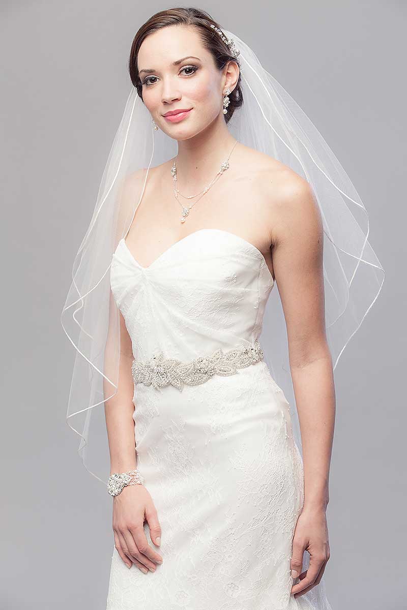 Portrait of classic minimalist bride wearing simple yet pretty Opulence Two Tier Fingertip Veil by Laura Jayne Accessories Toronto. Made in Canada.