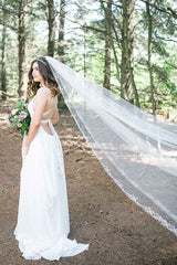 A statement cathedral veil with delicate swirls of silver embroidery and beading framing the edge and rising up the centre train