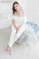 Cool bride seated wearing a long unique veil with feathers and crystal accents. Winona Cathedral Veil with Feathers Veil. Handcrafted in Canada by Laura Jayne Accessories Toronto.