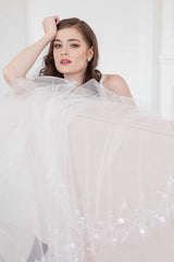 Glam shot of bride wearing Liliya Cathedral Veil draped over back of sofa.