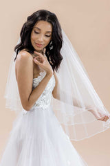 Bride looking down with Laura Jayne Jess Fingertip Beaded Edge Veil draped over one shoulder. Veil handcrafted in Toronto, Canada.