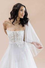 Bride wearing a fingertip veil draped over her shoulders. Jess Beaded Edge Fingertip Veil by Laura Jayne. Handmade in Canada.