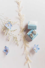 Styled image of Ferra tulle pearl headband with earrings in ringbox and flowers