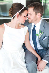 Profile of bride wearing beaded hair ribbon seated with groom