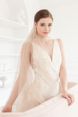 Bride wearing fingertip length veil in rose gold color with all-over glitter detail. Aurelie Fingertip Veil by Laura Jayne Accessories Toronto.