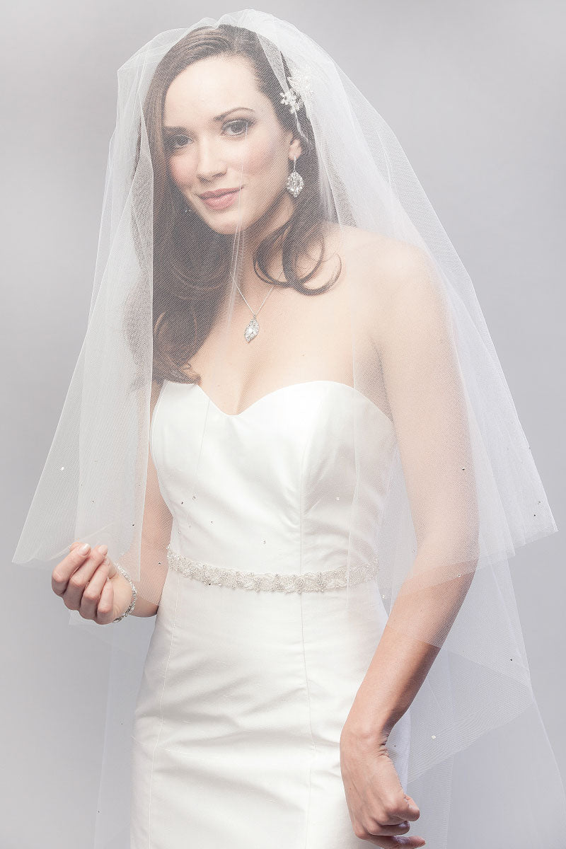 Profile of modern romantic bride wearing  a sheer chapel length veil with blusher over her face. Karina Crystal Border Chapel Veil by Laura Jayne. Handcrafted in Toronto, Canada.
