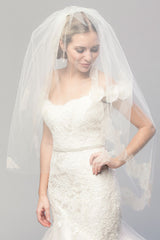 Modern romantic bride wearing a sheer fingertip length blusher veil over her face. Coco Chantilly Fingertip Cage Veil by Laura Jayne Accessories Toronto. Handcrafted in Canada.