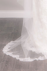 Close up of French lace with rose pattern on blush pink Bree Chapel Length Chantilly Lace Veil by Laura Jayne. Made in Toronto, Canada.