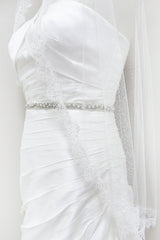 Bodice view of classic mantilla fingertip length veil with wild rose and leaf floral lace edging. Hayley Fingertip Alencon Mantilla Veil by Laura Jayne. Handcrafted in Canada.