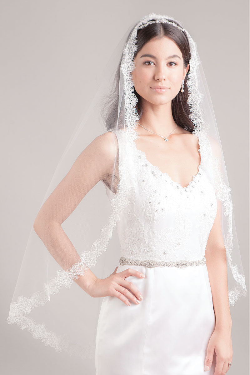Modern minimalist bride wearing a romantic fingertip length mantilla veil with lightly corded border of French Alencon rose lace. Hayley Fingertip Alencon Mantilla Veil by Laura Jayne. Handcrafted in Canada.