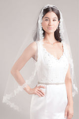 Modern minimalist bride wearing a romantic fingertip length mantilla veil with lightly corded border of French Alencon rose lace. Hayley Fingertip Alencon Mantilla Veil by Laura Jayne. Handcrafted in Canada.