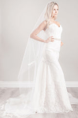 Romantic bride wearing a modern, slim flutter cut cathedral length veil with delicate crystals and French Alencon floral lace at the crown and around the edge. Made in Canada. Romantique Lace Cathedral Veil by Laura Jayne Accessories Toronto.