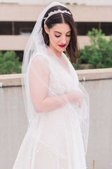 Bride looking down wearing a fine illusion tulle fingertip pearl bridal veil. Pandora Pearl Fingertip Veil. Handcrafted in Canada by Laura Jayne.