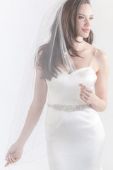 Modern romantic bride wearing a strapless bridal gown with a sheer fingertip wedding veil featuring a hand-beaded pearl and crystal border. Lavinia Beaded Fingertip Veil by Laura Jayne. Bridal veil made in Toronto, Canada.