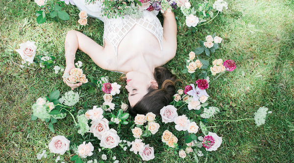 woman lying on grass surrounded by flowers