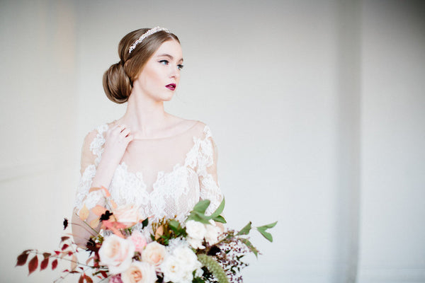 bride wearing a headpiece and holding a flower bouquet 
