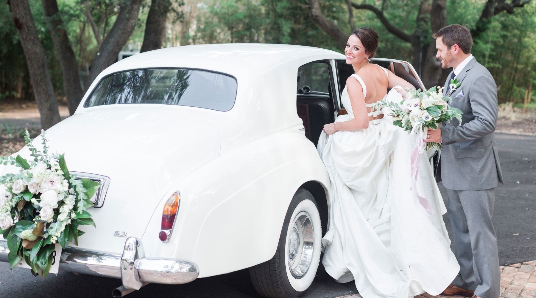 happy bride and groom getting ready to sit in a car 