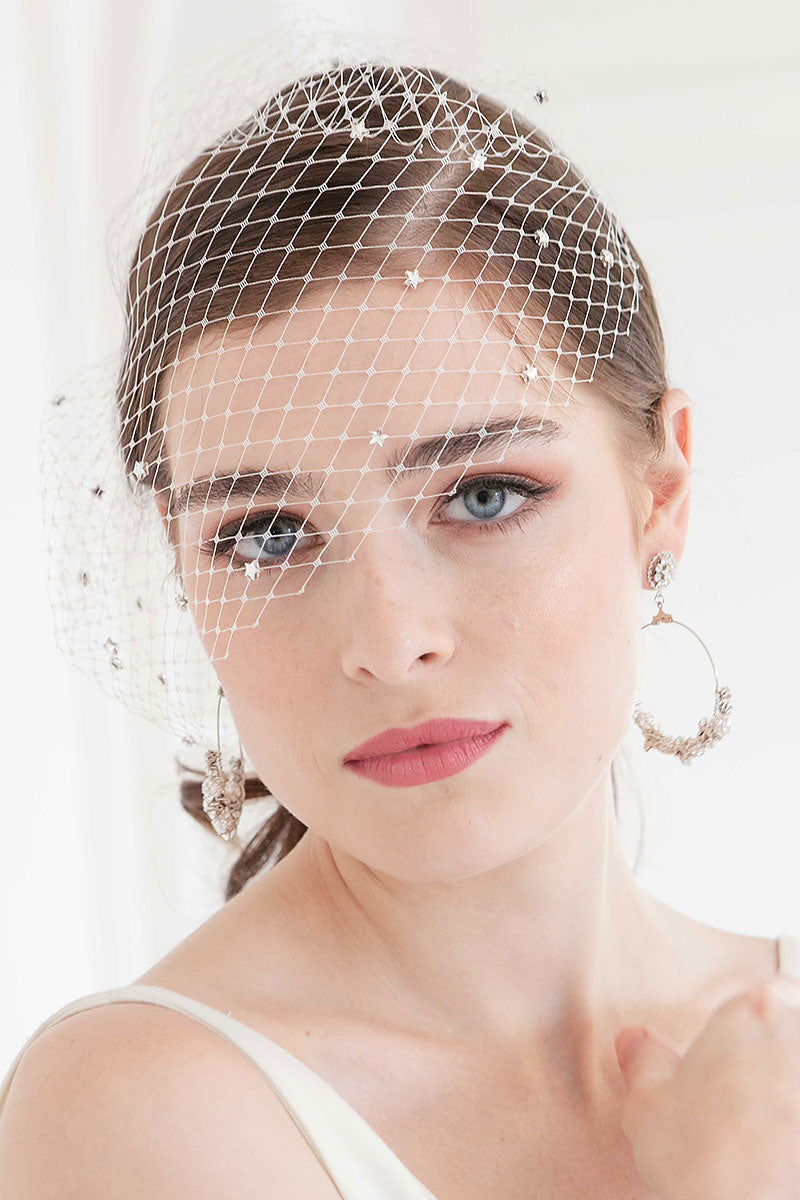 Birdcage face veil with crystal stars on woman with hoop earrings