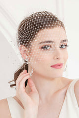 Bride slightly smiling wearing Nova crystal star birdcage veil with hand touching earring