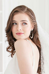 Profile of bride wearing modern pearl crystal hoop earrings with dot tulle veil