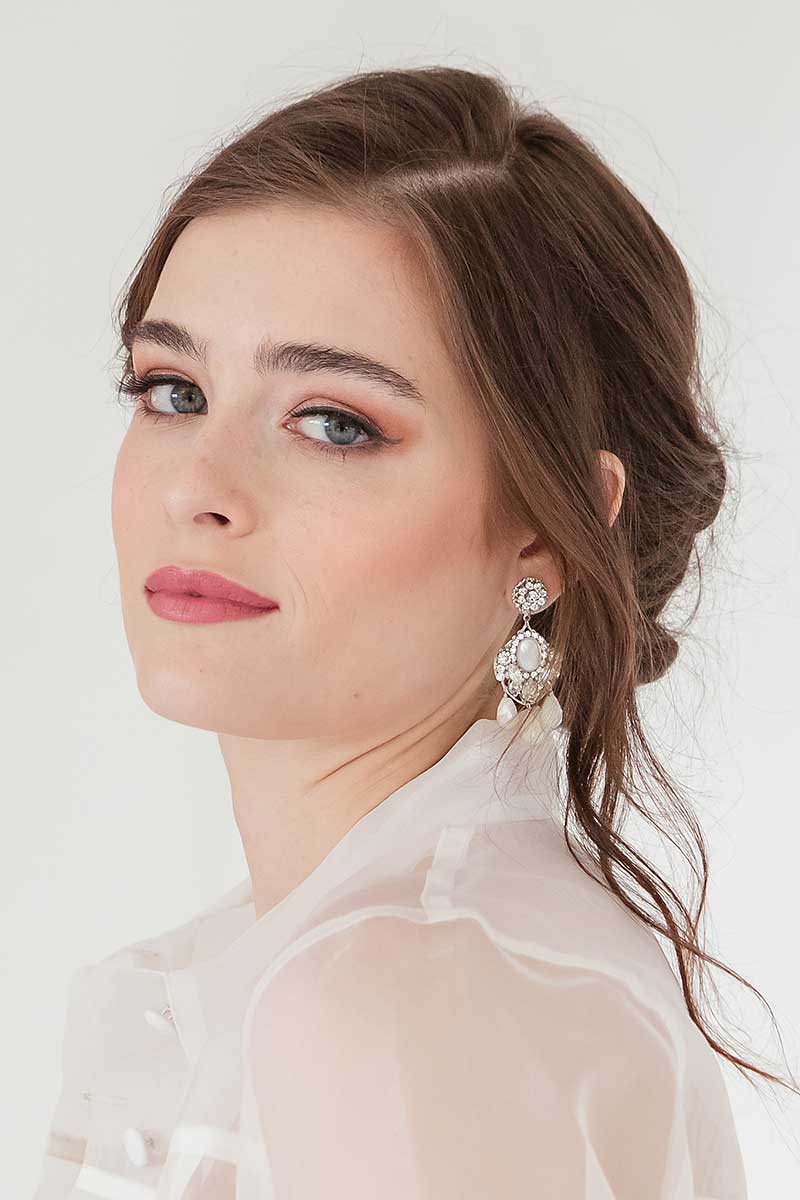 Woman wearing statement filigree crystal mother of pearl earrings