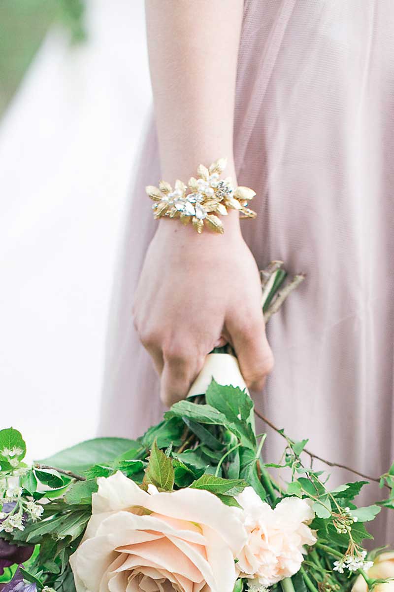 Woman holding bouquet with Filippa gold leaf hair vine styled as cuff