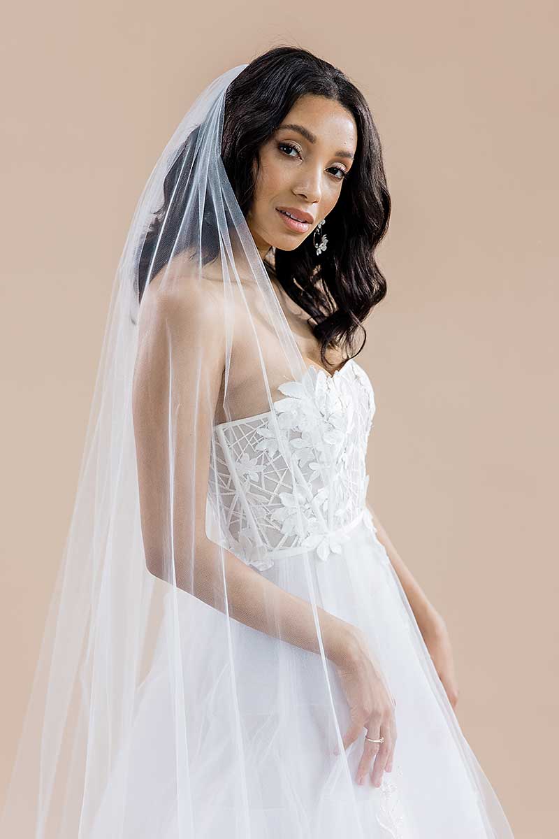 Side profile of a modern romantic bride wearing a strapless dress with the Monet Beaded Blossom Cathedral Veil draped over her shoulder. Laura Jayne Accessories Toronto. Made in Canada.