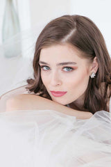 Bride leaning up against sofa wearing e7023 crystal pearl stud wedding earrings by Laura Jayne Accessories