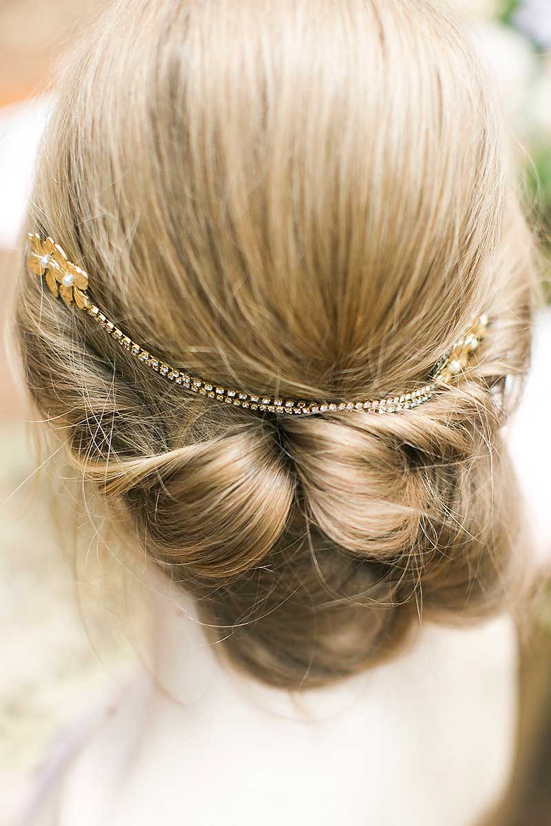 Back of woman's head with messy bun and draped chain flower headpiece