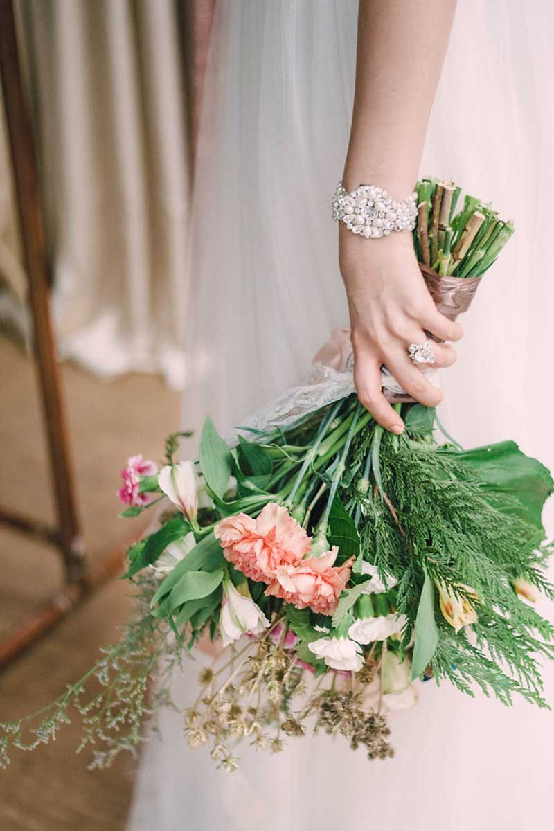 Bride holding bouquet wearing Laura Jayne Greta pearl cystal statement wedding bracelet