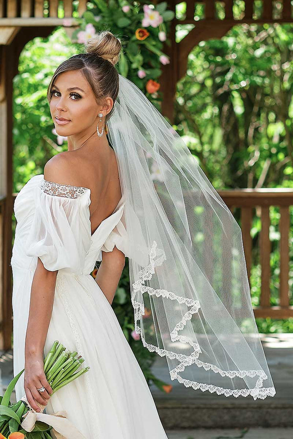A modern bride wearing a boho chic wedding gown and pretty fingertip length bridal veil with embroidered scallop lace trim. Julia Fingertip Venise Lace Veil by Laura Jayne Accessories Toronto. Handmade in Canada.