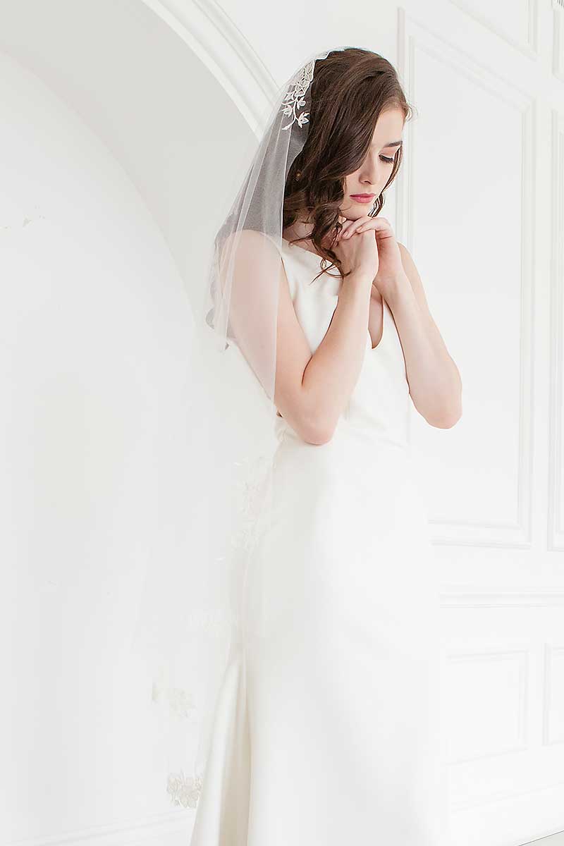 Side front view of bride wearing a floral embroidered waltz length wedding veil. Rosalie Mantilla Veil by Laura Jayne Accessories.