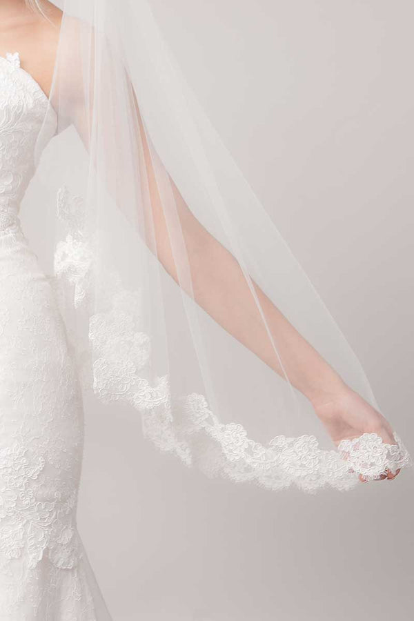 Bride's arm holding edge of French Alencon lace fingertip length veil. Marlisa by Laura Jayne Accessories Toronto. Handcrafted in Canada. 