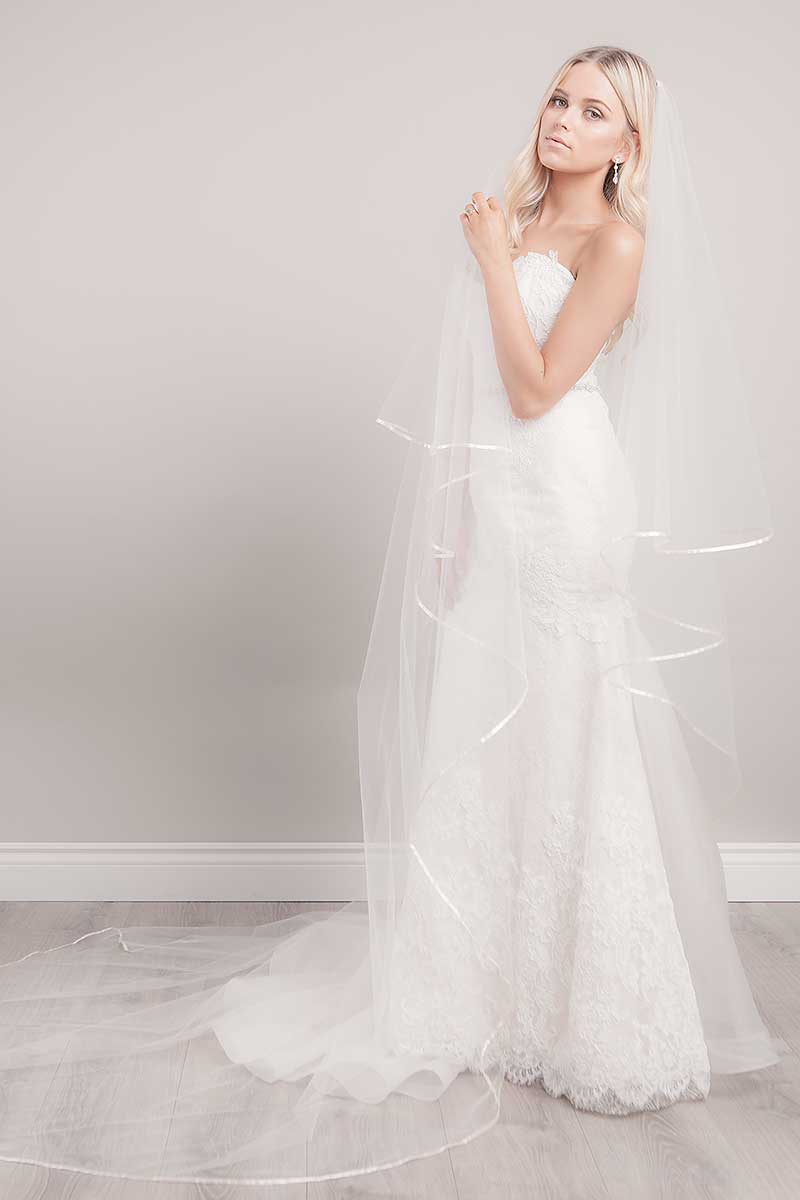 Full length view of bride wearing ivory cathedral length veil with satin ribbon. Miranda Ribbon Edge Cathedral Veil with blusher. Handmade in Canada. 