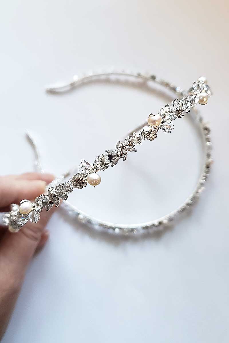 Close up of Sleek pearl crystal CZ headband by Laura Jayne Accessories upright in woman's hand