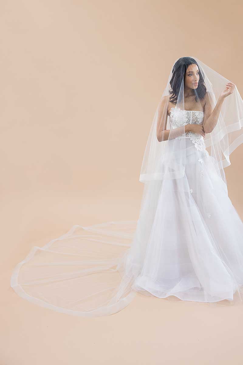 Portrait of bride wearing cathedral length horsehair trimmed veil with blusher over face. Heather by Laura Jayne Accessories