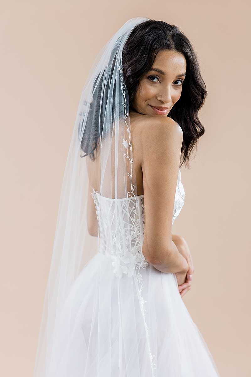 A modern romantic bride wearing a statement cathedral length veil featuring a pretty border of beaded flowers and vines. Bisous Floral Cathedral Veil by Laura Jayne Accessories Toronto. Handmade in Canada.