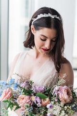 Woman with head down wearing Ferra pearl headband and holding bouquet