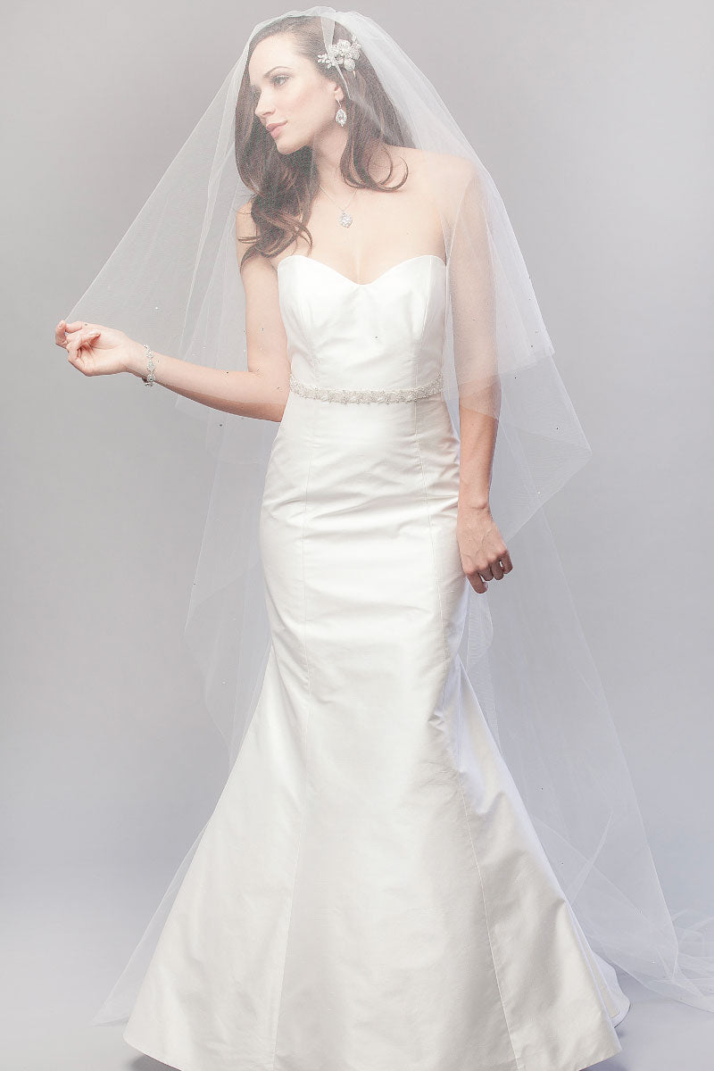 Full length image of classic bride wearing a minimalist chapel length veil with blusher over her face. Karina Crystal Border Chapel Veil made in Canada by Laura Jayne Associates Toronto.