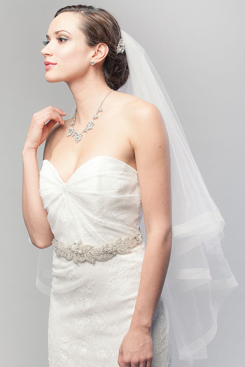 Profile view of bride wearing two-tier horsehair fingertip wedding veil by Laura Jayne. Denyse Horsehair Ribbon Fingertip Wedding Veil. Handmade in Canada.