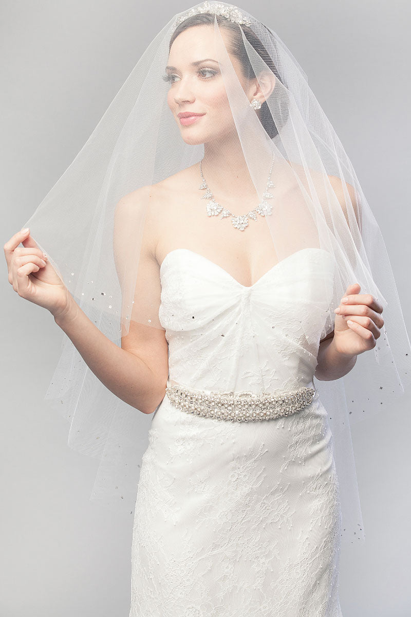 Modern minimalist bride wearing a simple strapless wedding dress and a chic fingertip length veil with blusher over her face. Lucille Crystal Fingertip Drop Veil by Laura Jayne Accessories Toronto. Handcrafted in Canada.