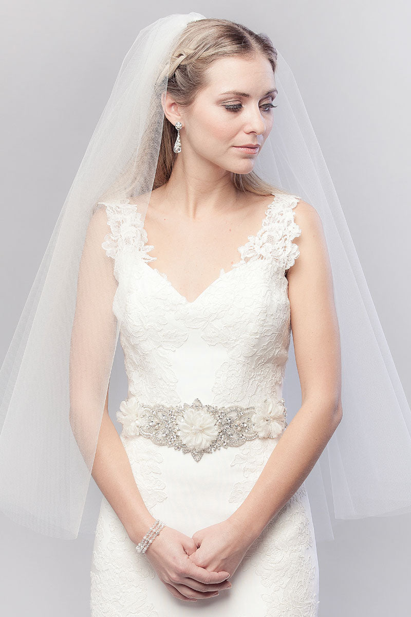 Wider view of modern minimalist bride wearing a sheer oval cut fingertip bridal veil. Annastacia Fingertip Veil by Laura Jayne. Handcrafted in Toronto, Canada.